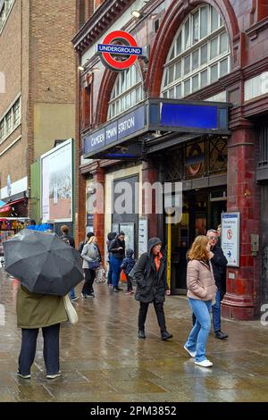 Camden Town, London: Outside Camden Town tube station on Camden High Street. People standing by the underground station in the rain. Stock Photo