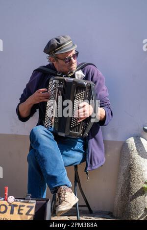 An old man playing accordion in front of the traditional market of Pornic Stock Photo