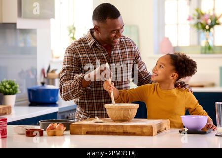 Family Shot With Father And Daughter Baking At Home In Kitchen Mixing Ingredients In Bowl Stock Photo