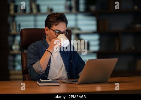 Hard-working young man employee working late at home office Stock Photo