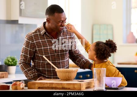 Family Shot With Father And Daughter Having Messy Fun Baking At Home In Kitchen Stock Photo