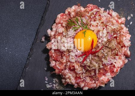 Homemade minced meat, spices and herbs. Traditional raw ingredients for cooking cutlets or meatballs. Trendy hard light, dark shadow, light stone conc Stock Photo