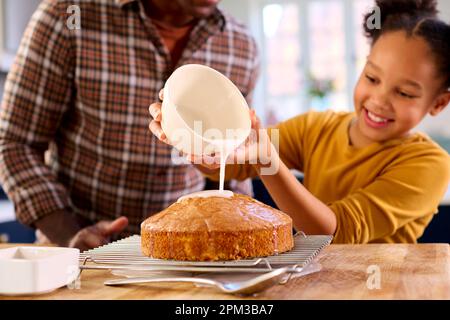 Family Shot With Father And Daughter Baking At Home In Kitchen Decorating Cake With Icing Stock Photo