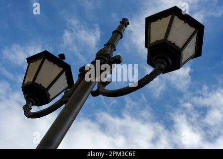 Photo of a retro style street light against blue sky with some clouds Stock Photo