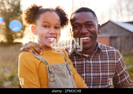 Portrait Of Smiling Father And Daughter Outdoors In Autumn Countryside Against Flaring Sun Stock Photo