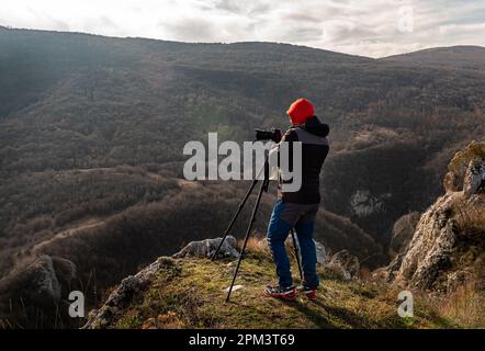 Photographer taking photographs with digital camera on a tripod in mountains. Travel and active lifestyle concept Stock Photo