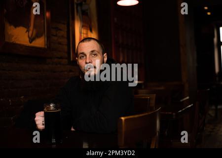bearded man holds glass of beer while sitting in pub. Beer time. Alcohol drinks Stock Photo