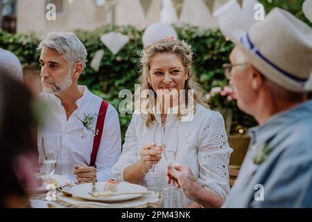 Mature bride and groom toasting with family at wedding reception outside in the backyard. Stock Photo