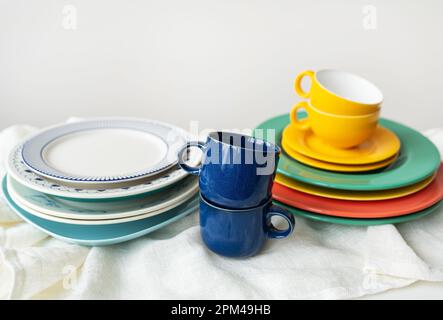 A pyramid of brightly colored bowls, plates and cups of different sizes and colors on the kitchen table. Scandinavian style, minimalism. Preparation f Stock Photo