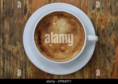 A cappuccino cup on a wooden table with a creme brulee top. Stock Photo