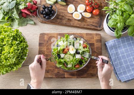 Top view of female hands mixing a healthy spring salad made from various ingredients. Concept of healthy lifestyle. Stock Photo