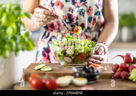 A portion of healthy salad on a fork in the hand of a young woman. Stock Photo