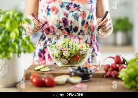 Female hands mixing a healthy spring salad made from various ingredients. Concept of healthy lifestyle. Stock Photo