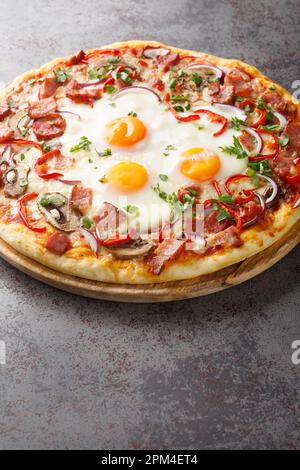 Australian traditional pizza with ham and eggs close-up on a wooden board on the table. Vertical Stock Photo
