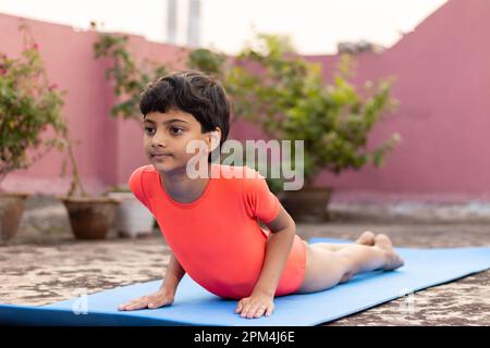 An Indian girl child practicing yoga on yoga mat outdoors Stock Photo -  Alamy
