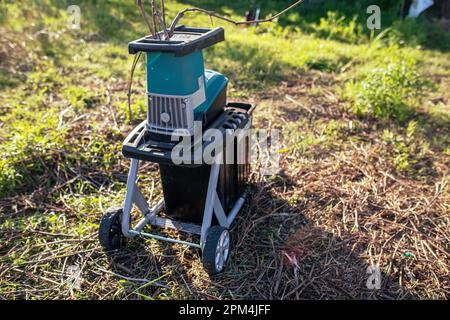 electric garden grinder to shred with a extended filled tank for crushed branches, ready for use in solid fuel boilers, or as mulch for garden work. Stock Photo