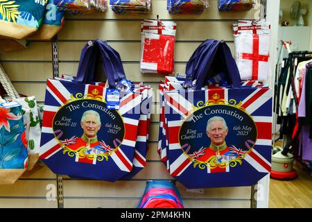 Tonbridge, Kent April 11th, 2023. Cheap £1 commemorative tote bags and flags for the upcoming Coronation of King Charles III for sale inside a charity shop.  King Charles III will be crowned alongside Camilla, the Queen Consort, on Saturday 6 May 2023 at Westminster Abbey in London. Stock Photo