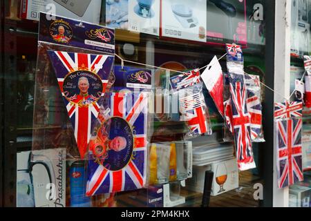 Tonbridge, Kent April 11th, 2023. Cheap Union Jack flags, bunting and other commemorative memorabilia for the upcoming Coronation of King Charles III for sale outside a hardware store. King Charles III will be crowned alongside Camilla, the Queen Consort, on Saturday 6 May 2023 at Westminster Abbey in London. Stock Photo