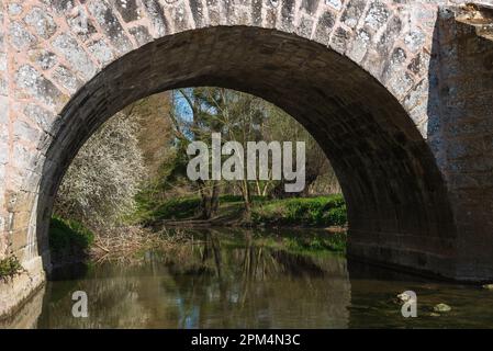 View through arch of Roman bridge on old royal road from Paris to Sens over Yerres river near medieval town of Brie-Comte-Robert. Stock Photo