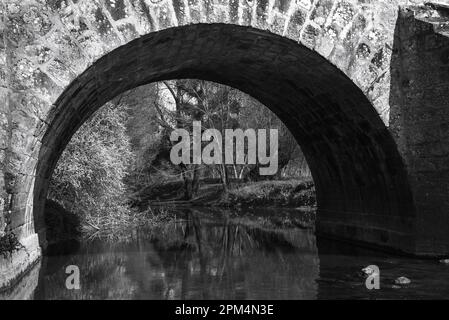 View through arch of Roman bridge on old royal road from Paris to Sens over Yerres river near medieval town of Brie-Comte-Robert. Black white photo Stock Photo