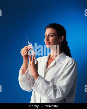 Female medical professional preparing hypodermic syringe. Stock Photo