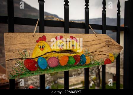 Colorful Easter eggs painted on wooden board on green grass and three yellow chickens close-up Stock Photo