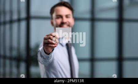 business man holding empty white business card in modern office building. Free blank copy space. Stock Photo