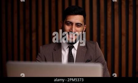 Handsome smiling latin man using laptop computer explaining something having video call. Stock Photo