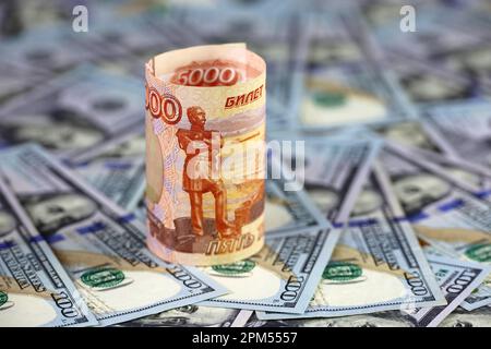 Russian rubles rolled up on background of US dollars. Concept of exchange rate, sanctions Stock Photo