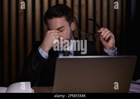 Tired young man feel pain eyestrain holding glasses rubbing dry irritated eyes fatigued from computer work Stock Photo