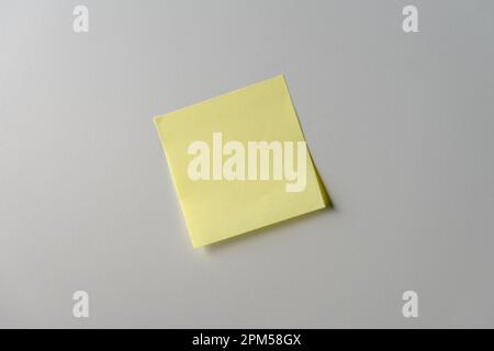 Yellow note paper on white background. Copy space. Close up. Stock Photo