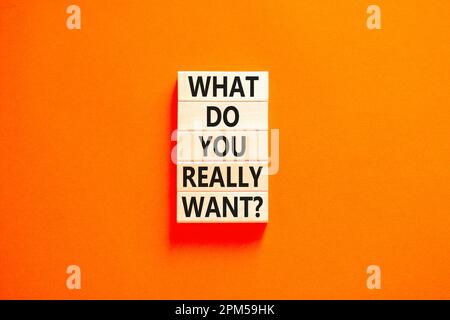 What do you really want symbol. Concept words What do you really want on wooden block. Beautiful orange table orange background. Business what do you Stock Photo