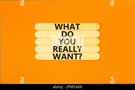 What do you really want symbol. Concept words What do you really want on wooden stick. Beautiful orange table orange background. Business and what do Stock Photo