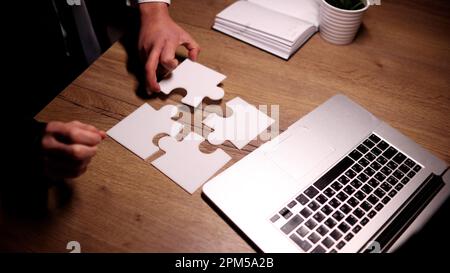 man putting together puzzles on wooden table Stock Photo