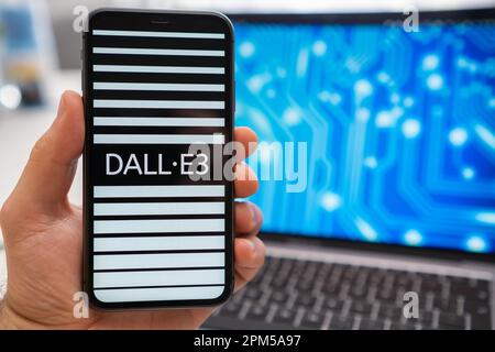 The screen of a smartphone held by a man shows DALL E3 neural network logo, while in the background, a laptop displays a splash screen with a neuronet. March 2023, Prague, Czech Republic  Stock Photo