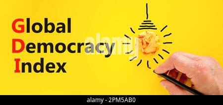 GDI global democracy index symbol. Concept words GDI global democracy index on paper on beautiful yellow background. Orange light bulb icon. Business Stock Photo