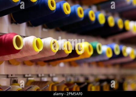 Multicolored sewing threads bobbins on stand in a shop. Selective focus. Stock Photo