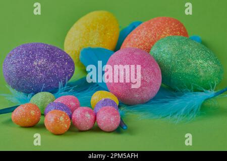 Colored Easter eggs and feathers on a green background. Stock Photo