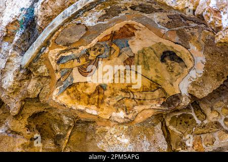 The Roman Baths of Salamis preserve, in this niche, the remains of a colourful 3rd-century-CE wall painting, possibly the well-known Hylas fresco in the sudatorium of the complex. A standing figure in blue robes holding a raised staff and a reclining figure are clearly visible. It once depicted the youth Hylas and the water nymphs to whom, according to Greek mythology, he fell victim. The bath complex lies near Yeni Boğaziçi, Turkish Republic of Northern Cyprus (TRNC). Stock Photo