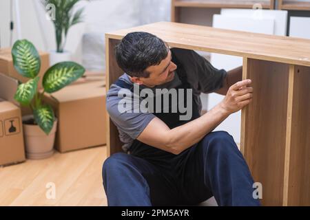 Skilled Craftsman Assembling Repairing Furniture in blue uniform for Beautifully Furnished Home. Stock Photo