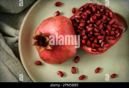 One cut pomegranate on green plate Stock Photo