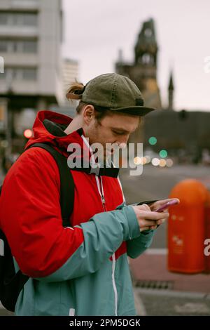 A young man tourist uses a navigator and a map on phone. Stock Photo