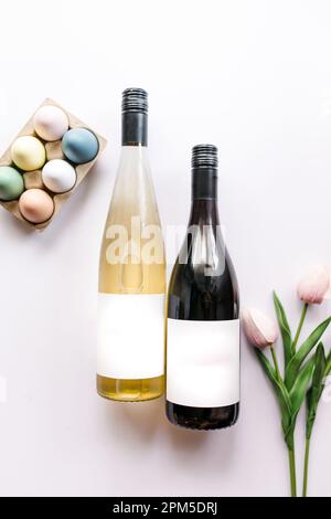 Carton of colorful fresh eggs, bottles of wine, pink tulips Stock Photo