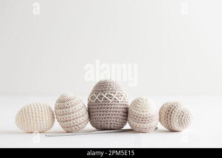 Row of cute striped pattern crocheted eggs, pastel color on a white Stock Photo