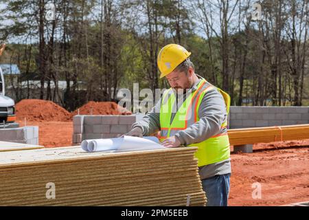 Experienced build engineer safety an holding in hands blueprint project doing monitoring construction proceeding on construction site Stock Photo