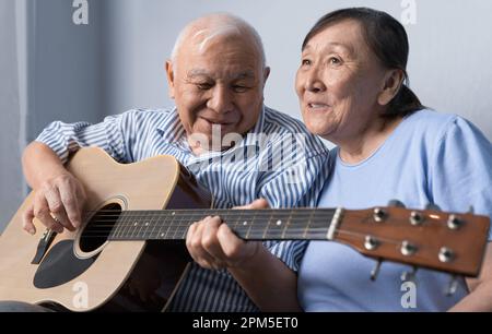Senior man playing acoustic guitar and singing with his wife Stock Photo