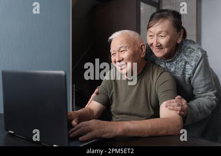 Senior couple at home using laptop for education or online shopping Stock Photo