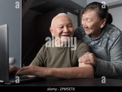 Senior couple at home using laptop for education or online shopping Stock Photo
