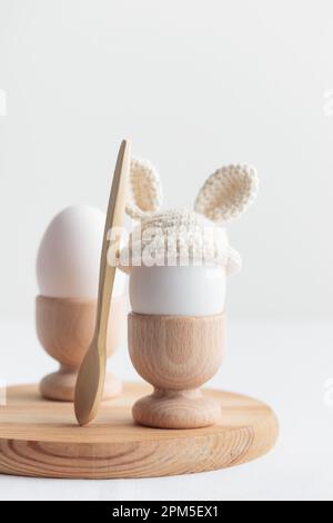easter egg in crochet hat with bunny ears in wooden egg holder Stock Photo