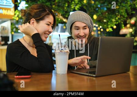 Asian couple sitting at a table in a restaurant and working with Stock Photo